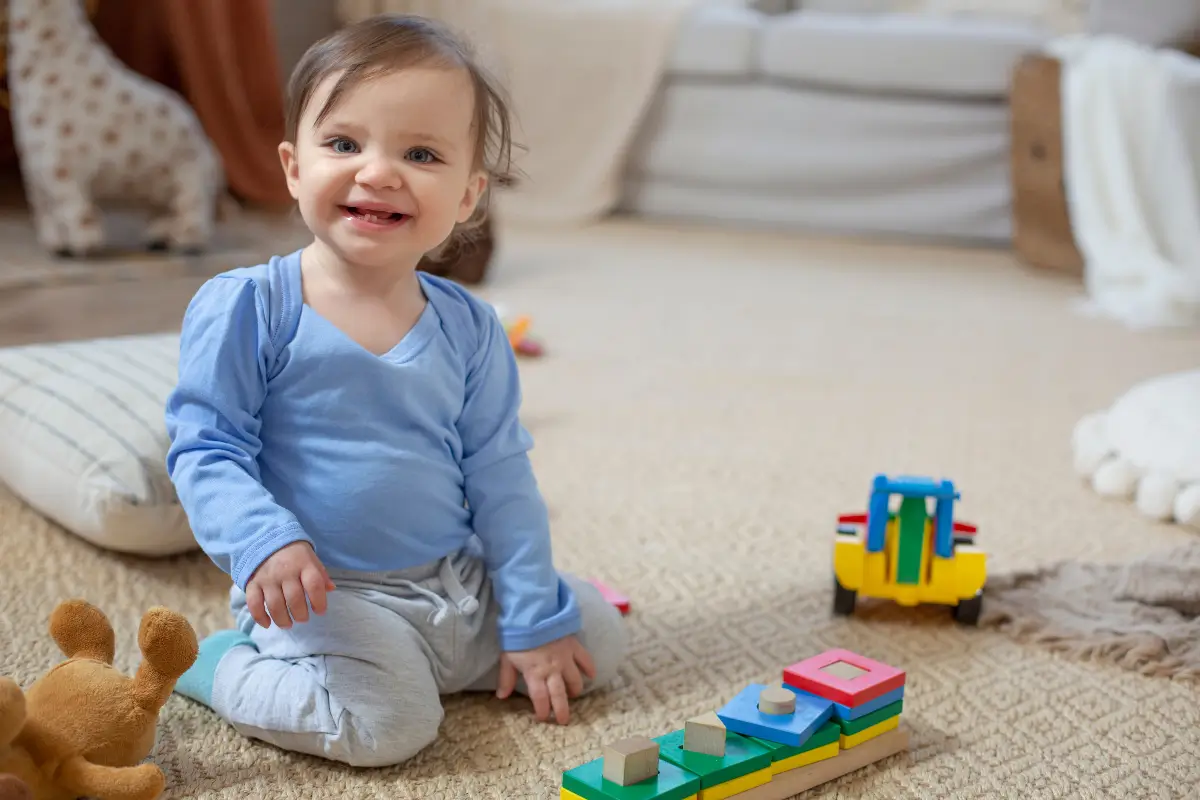 Atividades para crianças - criança sentada no chao com brinquedos ao redor